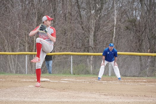 A high school baseball pitcher delivering a pitch during a game outdoors.